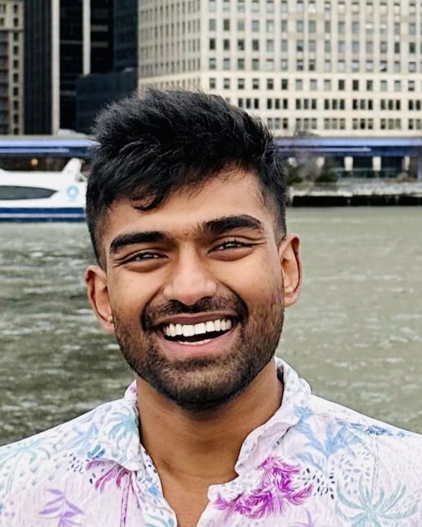 Ashish Chandrashekar, smiling, with the Manhattan waterfront behind him